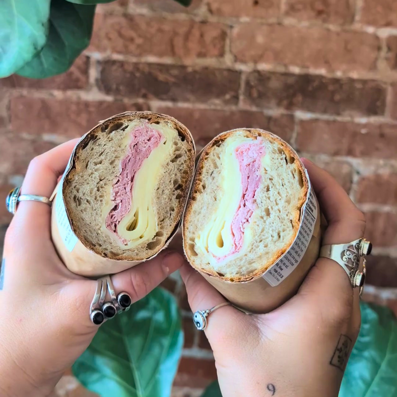 hands holding halved jambon beurre sandwich
